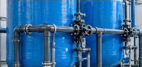 Row of blue pressure filter vessels and header pipework in a water treatment plant
